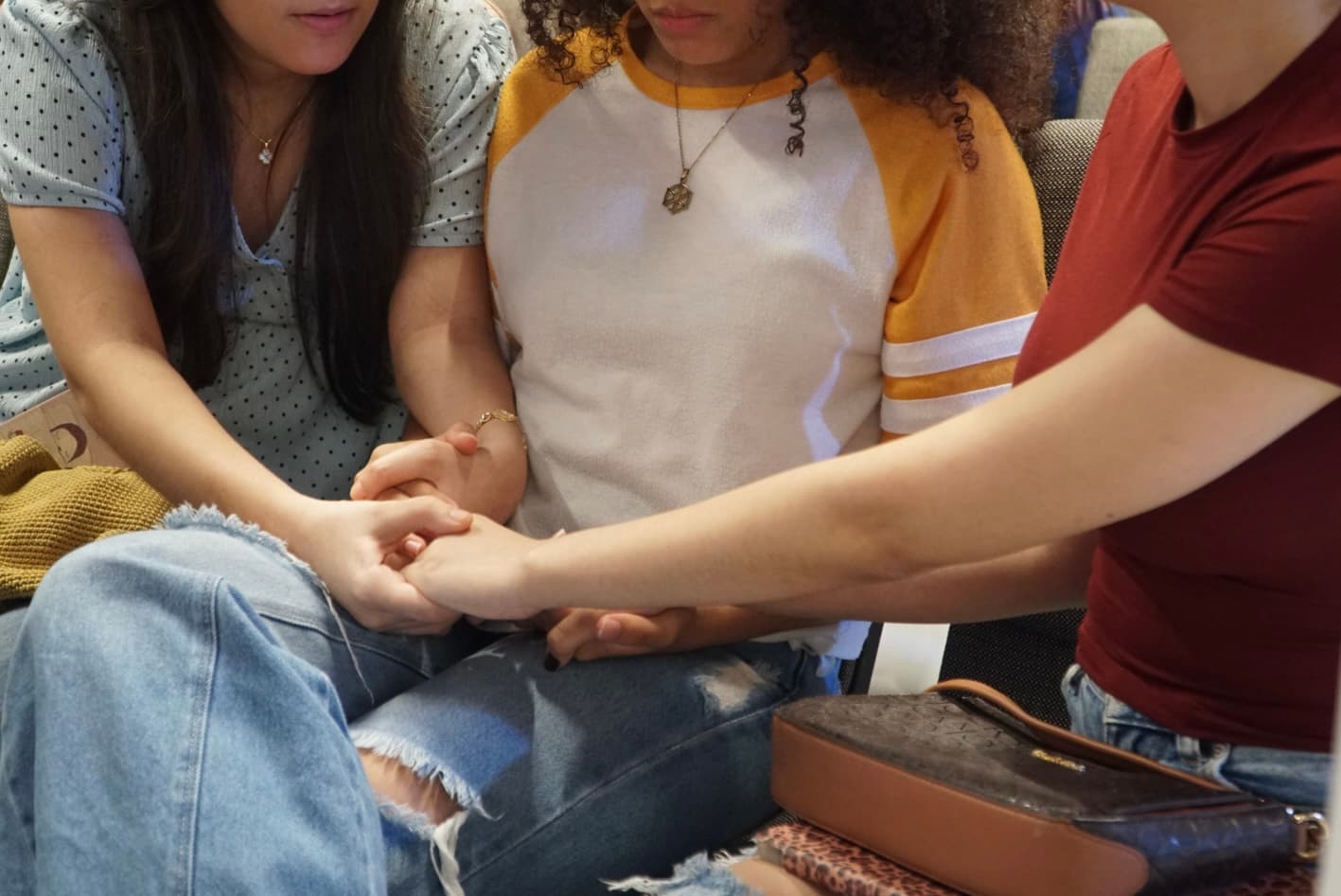 Tres personas orando tomadas de la mano